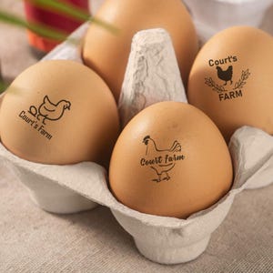 May include: Four brown eggs in a cardboard egg carton. The eggs are stamped with a black and white chicken and the text 