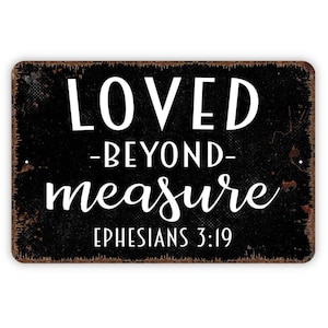 May include: A rectangular metal sign with a distressed black finish and rusted edges. The text reads LOVED -BEYOND- measure in white, with EPHESIANS 3:19 printed in a smaller white sans-serif font at the bottom of the sign.