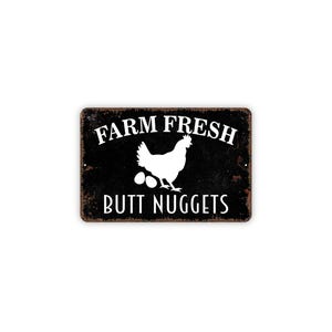 Puede incluir: Un letrero rectangular de metal negro con acabado desgastado que presenta la silueta blanca de una gallina sobre dos huevos. El texto FARM FRESH est&aacute; impreso en blanco arriba y el texto BUTT NUGGETS est&aacute; impreso debajo.