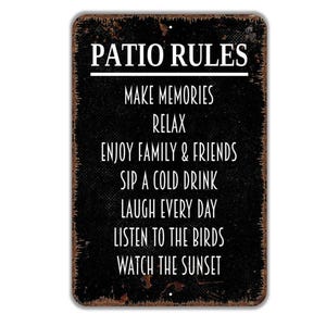 May include: A rectangular metal sign with a distressed black finish and rust-colored edges. The white text reads: PATIO RULES, MAKE MEMORIES, RELAX, ENJOY FAMILY & FRIENDS, SIP A COLD DRINK, LAUGH EVERY DAY, LISTEN TO THE BIRDS, WATCH THE SUNSET.