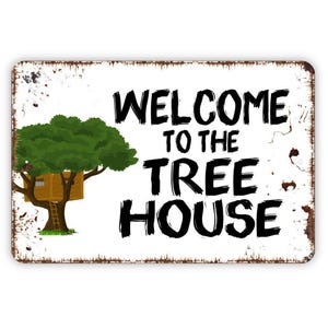May include: A rectangular metal sign with a white background and distressed rust-colored edges. The sign features a graphic of a brown wooden tree house in a green tree and the black text "WELCOME TO THE TREE HOUSE" printed on the right side.
