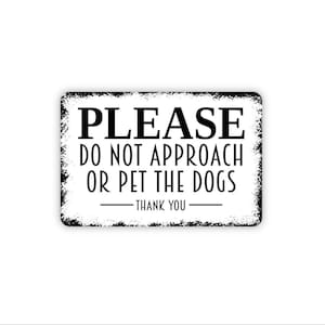 May include: A rectangular white sign with a distressed black border and black text that reads: PLEASE DO NOT APPROACH OR PET THE DOGS - THANK YOU. The sign features a clean, sans-serif font for the main message and a bold serif font for the word PLEASE.