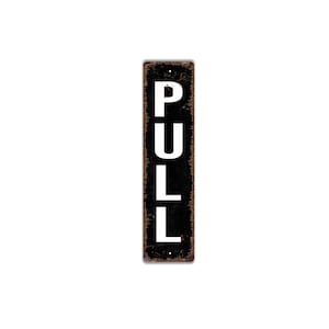 May include: A rectangular, vertical sign with the word "PULL" in large, white capital letters against a black background. The sign has a distressed, vintage appearance with a rusty brown border.