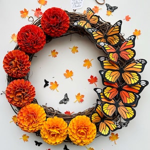 May include: A handmade wreath with a grapevine base, adorned with paper flowers in shades of red and orange, and paper butterflies. Scattered around are paper maple leaves and small black butterflies. The wreath has a tag that says "Floral Studio".
