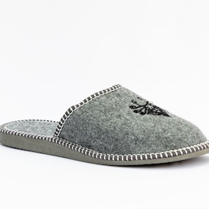 May include: Gray felt slippers with a white stitched trim and a black embroidered design of a deer head.
