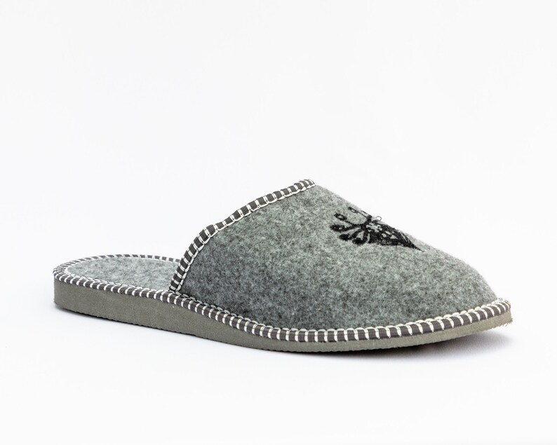 May include: Gray felt slippers with a white stitched trim and a black embroidered design of a deer head.