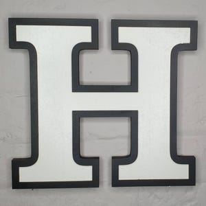May include: White letter H with a thick black border. The letter is made of wood and is a decorative piece.