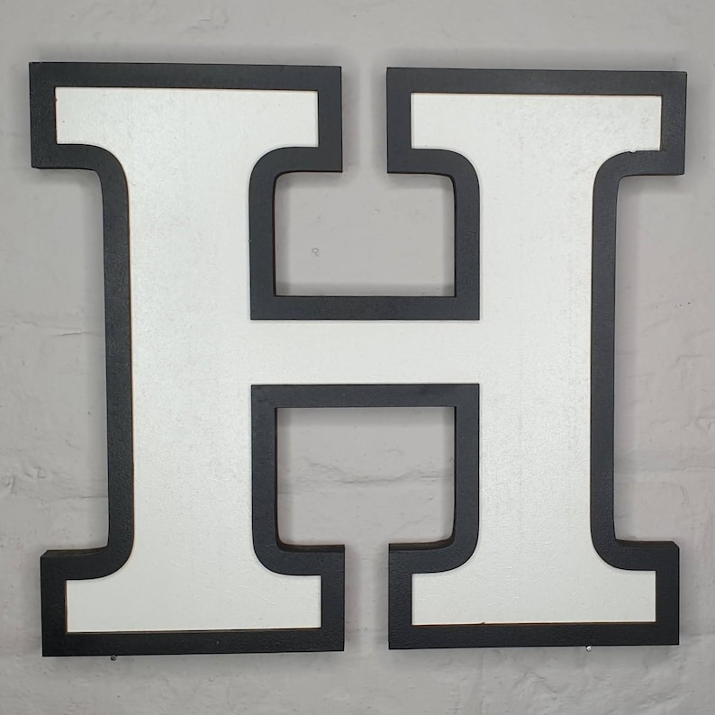 May include: White letter H with a thick black border. The letter is made of wood and is a decorative piece.