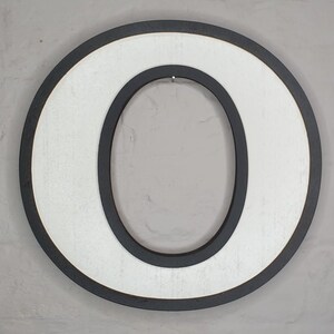 May include: White wooden letter O with a black outline. The letter is painted white and has a black border around the outside edge and around the inside of the letter.