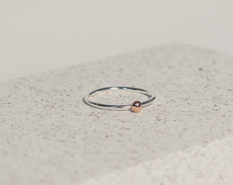 Peut inclure: Une simple bague en argent avec un petit accent de perle dorée.