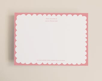 May include: A pink scalloped-edge notepad with the text "FROM THE DESK OF LILA PINNOCK" in the center. The address "743 MAPLEBERRY DRIVE, AMBER FALLS, WY 63846" is printed at the bottom. The notepad has a white interior.