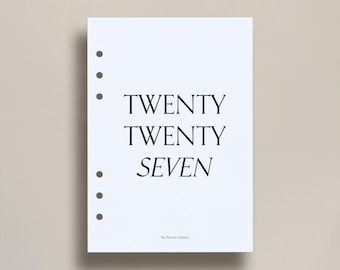 May include: A white planner page with the text "TWENTY TWENTY SEVEN" in a bold, serif font. The page has several pre-punched holes for binding and the text "The Peacock Collector" at the bottom.
