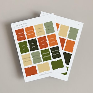 May include: A sheet of 12 colourful monthly journal tabs with rounded corners. The tabs are in shades of orange, green, and beige. The text on the tabs reads "January", "February", "March", "April", "May", "June", "July", "August", "September", "October", "November", and "December". The text "JOURNAL TABS" and "MATT STICKER SHEET" is at the top of the sheet. The text "THE PINNOCK COLLECTIVE" is at the bottom of the sheet.