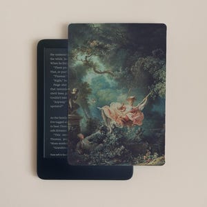 Op de afbeelding: E-reader met een decoratieve hoes met een klassiek schilderij van een vrouw op een schommel in een tuin. Het kunstwerk gebruikt zachte pastelkleuren, met de nadruk op de roze jurk van de vrouw en het weelderige groen.