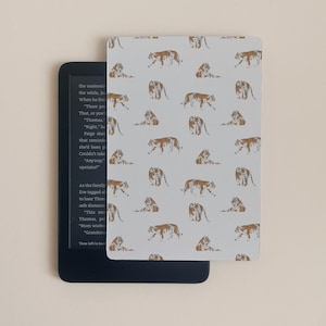 Peut inclure: Une housse de liseuse gris clair avec un motif répété de tigres orange et noirs dans diverses poses. La housse est placée sur un appareil de liseuse noir, avec du texte visible à l'écran.