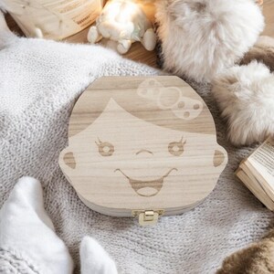K&ouml;nnte beinhalten: Eine h&ouml;lzerne Zahnfee-Box mit einem M&auml;dchen-Gesicht, das in den Deckel graviert ist. Die Box ist hellbraun und hat einen kleinen goldenen Verschluss.