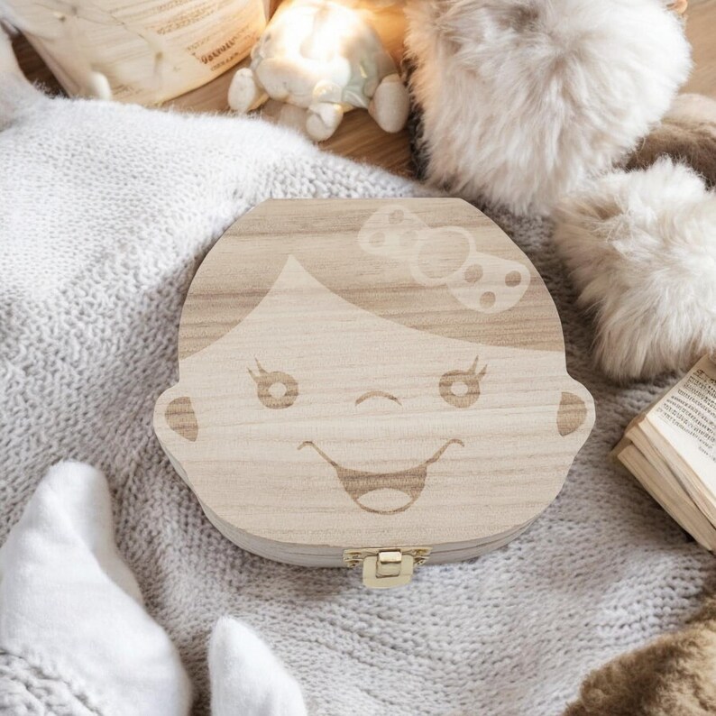 K&ouml;nnte beinhalten: Eine h&ouml;lzerne Zahnfee-Box mit einem M&auml;dchen-Gesicht, das in den Deckel graviert ist. Die Box ist hellbraun und hat einen kleinen goldenen Verschluss.