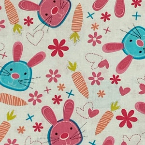 Puede incluir: Una tela blanca con un patrón repetido de conejos rosas y azules, zanahorias, flores y corazones. Los conejos tienen orejas rosas y narices azules. Las zanahorias son naranjas y verdes. Las flores son rosas y blancas. Los corazones son rosas.