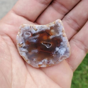 May include: A brown and white agate geode with a natural, irregular shape. The geode has a white outer layer and a brown inner layer with white veins.