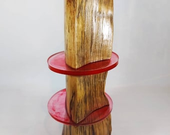 May include: A unique wooden sculpture with a natural wood grain finish. The sculpture features two red, circular accents. The piece is a vertical design, showcasing the natural beauty of the wood and the vibrant red accents.