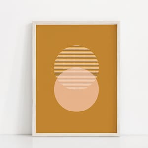 Può includere: Una stampa incorniciata con un design minimalista che presenta due cerchi sovrapposti. Il cerchio più grande è giallo senape con strisce bianche, e il cerchio più piccolo è pesca con strisce bianche.