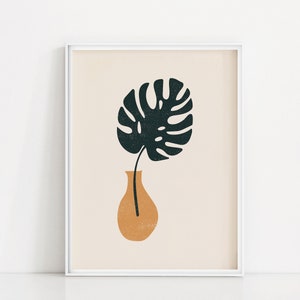 May include: A white framed print with a minimalist illustration of a single green leaf in a terracotta vase on a beige background.