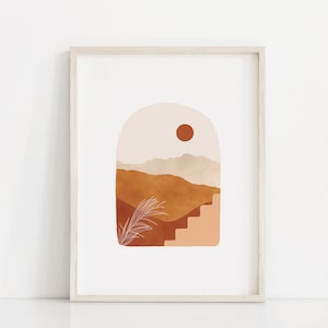 May include: Abstract art print featuring a stylized landscape with a sun, mountains, and a staircase in shades of brown, orange, and beige. The print is framed in a light wood frame.