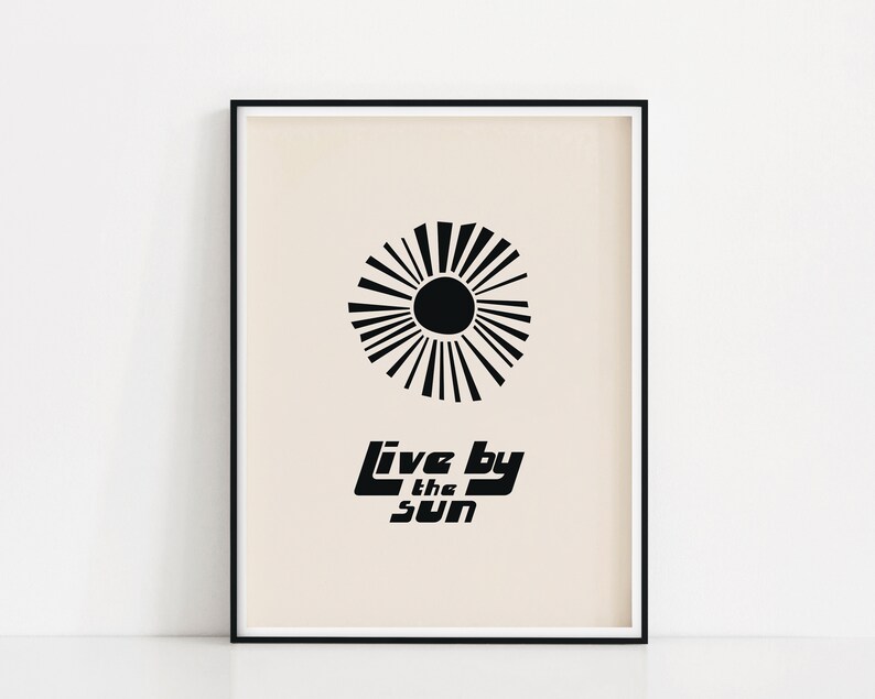 Puede incluir: Impresi&oacute;n en blanco y negro con un dise&ntilde;o de sol estilizado y el texto "Live by the sun" sobre un fondo beige.