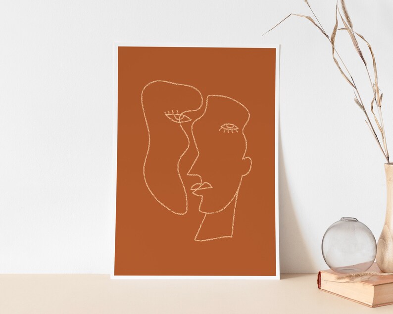 May include: Abstract line art print of two faces in a minimalist style on a burnt orange background.