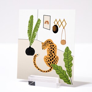 May include: A digital illustration of a leopard sitting in a room with a potted plant, a hanging bag, and a wall-mounted rack with a rainbow design. The leopard is orange and black with a white background.