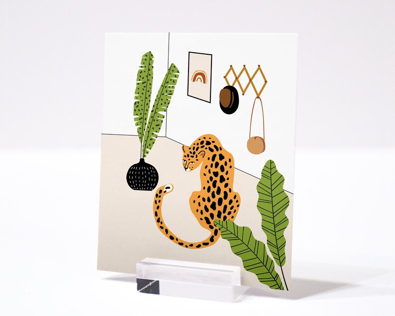 May include: A digital illustration of a leopard sitting in a room with a potted plant, a hanging bag, and a wall-mounted rack with a rainbow design. The leopard is orange and black with a white background.