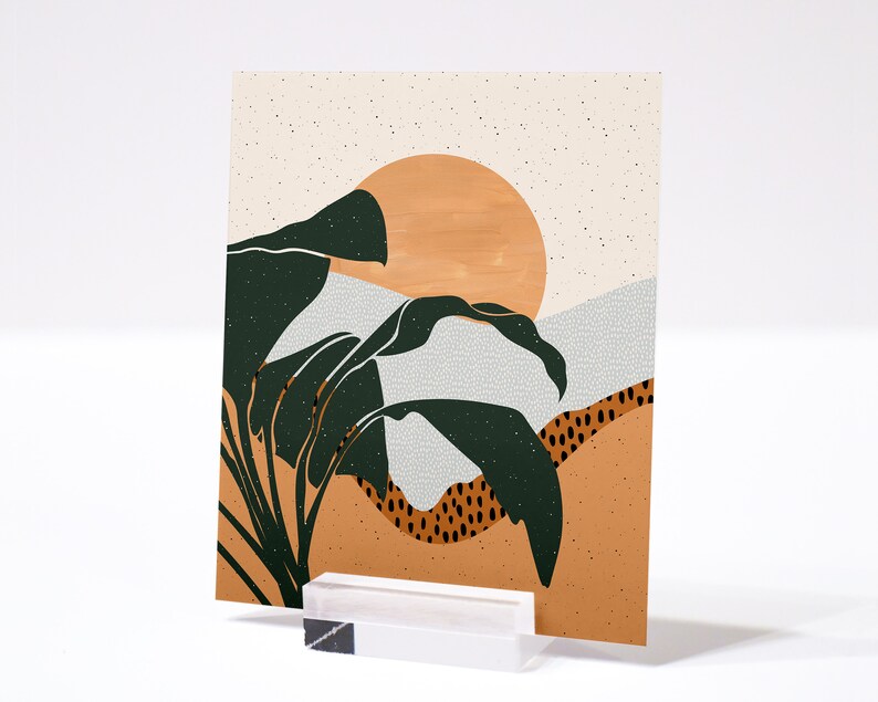 May include: Abstract art print featuring a stylised sunset with a large orange sun and green leaves. The background is a light beige with a subtle speckled texture.