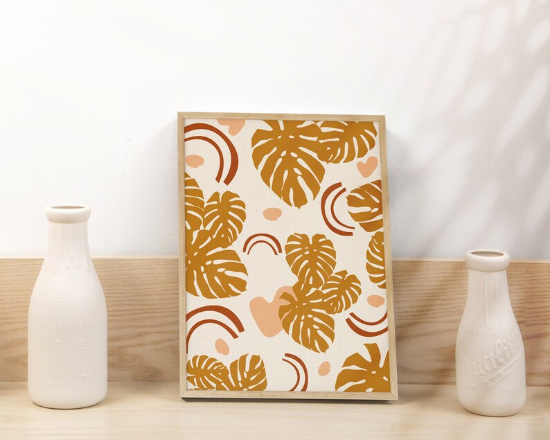 May include: A framed print with a white background and a pattern of brown leaves and pink shapes. The leaves are stylized and resemble monstera leaves.
