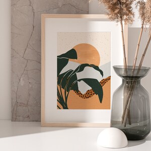 May include: A framed print with a minimalist design featuring a stylized sunset with green leaves and a light orange background.