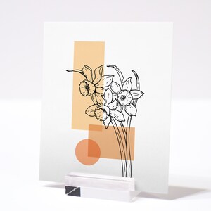 May include: A minimalist art print featuring a line drawing of daffodils in black against a background of peach and cream colored geometric shapes.