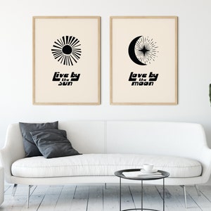 Puede incluir: Dos p&oacute;sters minimalistas en blanco y negro con un dise&ntilde;o de sol y luna. El texto en los p&oacute;sters dice "Live by the sun" y "Love by the moon".