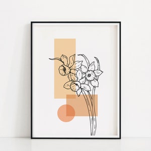 May include: A black and white line drawing of daffodils with peach and orange geometric shapes behind them. The image is framed in a black frame.