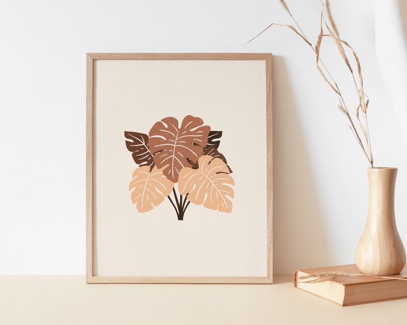 May include: A framed print with a minimalist design featuring a cluster of brown and orange tropical leaves on a cream background.