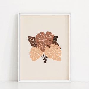 May include: A framed print with a minimalist design featuring a cluster of brown and peach monstera leaves on a cream background.