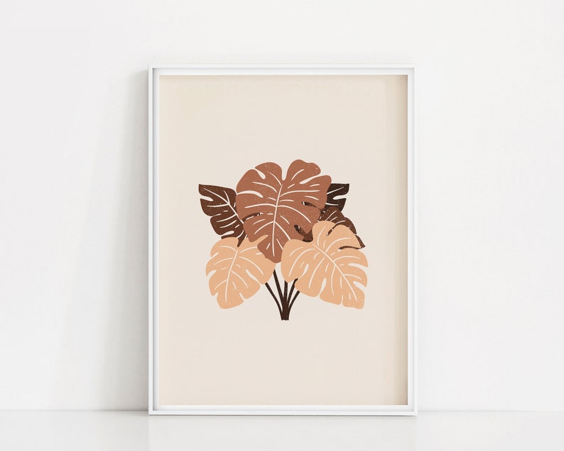 May include: A framed print with a minimalist design featuring a cluster of brown and peach monstera leaves on a cream background.