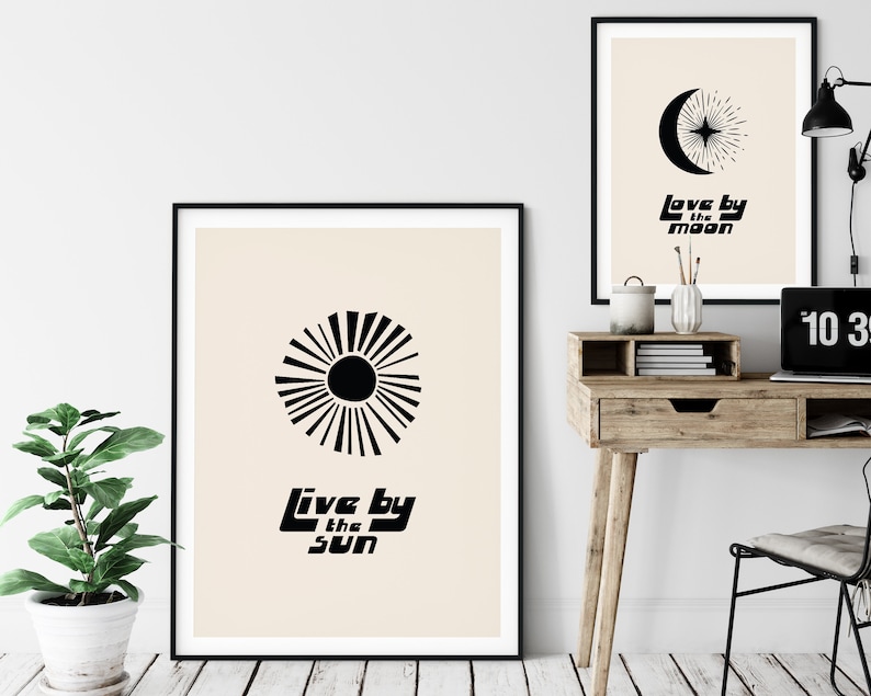 Puede incluir: Dos impresiones de arte minimalistas en blanco y negro con un dise&ntilde;o de sol y luna. La impresi&oacute;n del sol dice "Live by the sun" y la impresi&oacute;n de la luna dice "Love by the moon".