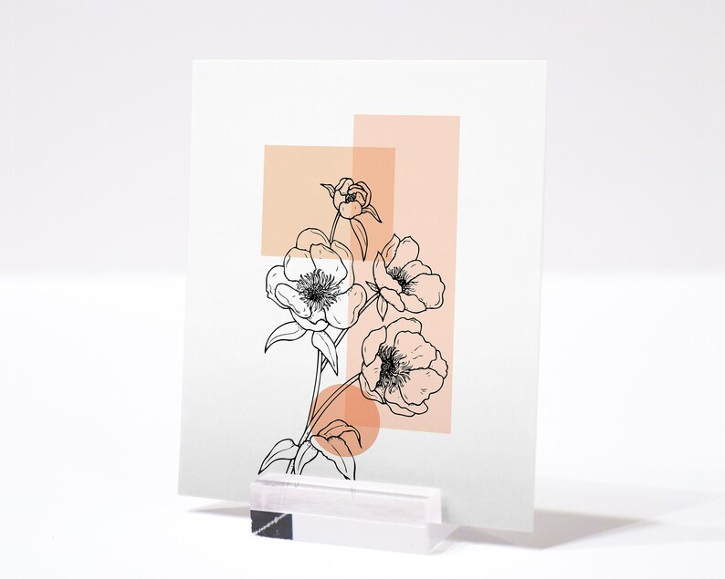 May include: A black and white line drawing of flowers with peach colored geometric shapes behind them. The image is printed on a white card.