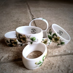 Peut inclure: Ensemble de six anneaux de serviette en céramique blanche avec un motif floral. Les anneaux sont décorés d'un motif floral délicat et des mots "Gloucester Fine Bone China Made in England".