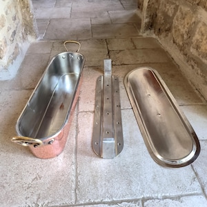 Puede incluir: Un molde rectangular para alimentos de cobre y acero inoxidable con tapa y un inserto separado. El molde tiene un exterior de cobre pulido y un interior de acero inoxidable. La tapa y el inserto son de acero inoxidable.