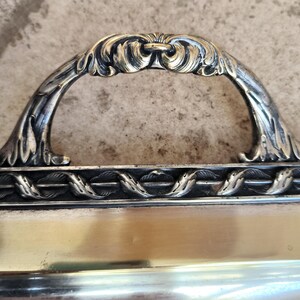 May include: A silver serving tray with an ornate handle. The handle is decorated with a floral design and has a gold finish.