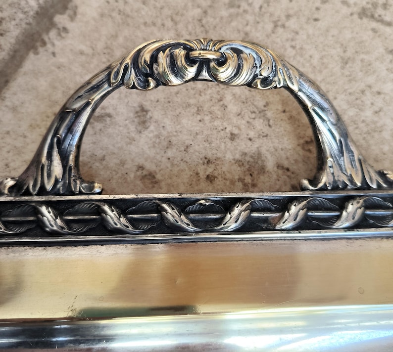 May include: A silver serving tray with an ornate handle. The handle is decorated with a floral design and has a gold finish.