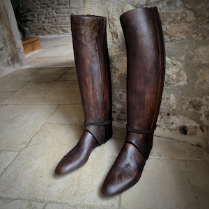 Può includere: Un paio di stivali in legno per stivali in pelle marroni. Gli stivali sono in legno e hanno una finitura marrone scuro. Sono progettati per aiutare a mantenere la forma degli stivali in pelle.