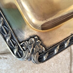 May include: A silver serving tray with a decorative border of stylized leaves and a gold-toned interior.