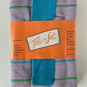 May include: A pack of purple and green striped fabric with a blue fabric tie. The pack is labelled "Tee-Set" and includes instructions for creating tops.