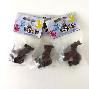Op de afbeelding: Drie bruine paardvormige knoppen in individuele doorzichtige plastic zakjes met kopkaarten gelabeld KIDS ROOM Decorative Hardware. Elke knop heeft een donkerbruine paardfiguur met een metalen schroef voor bevestiging op meubels.